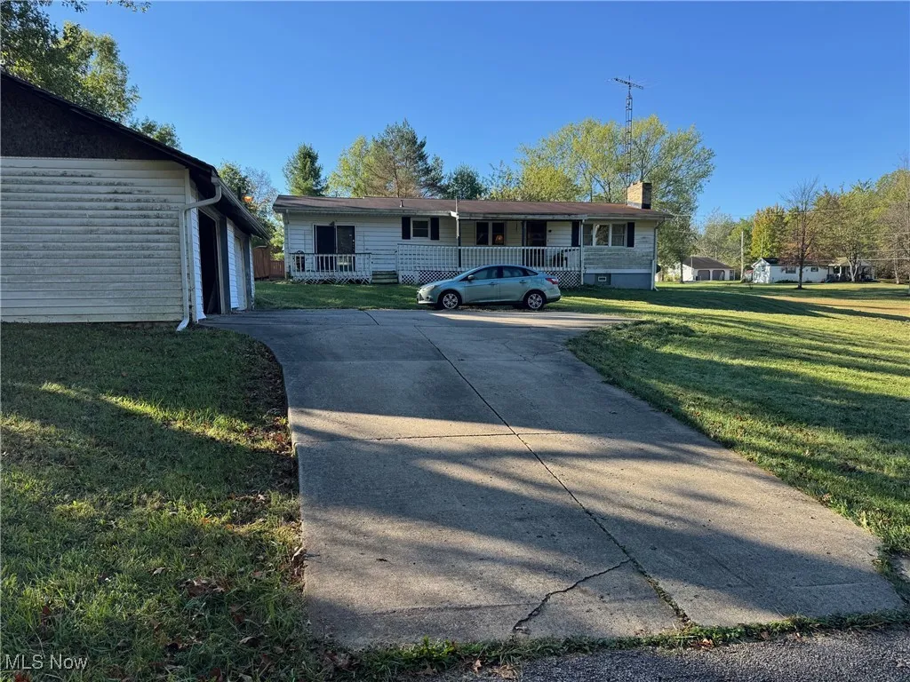 View of front of property featuring a front yard, an outdoor structure, a chimney, a garage, and concrete driveway