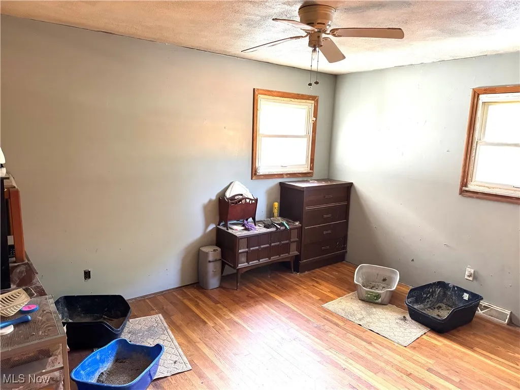 Bedroom featuring light wood finished floors, multiple windows, a textured ceiling, and ceiling fan