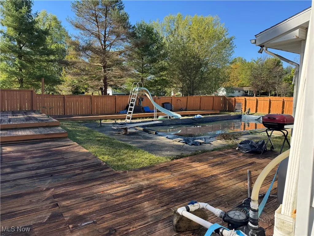 Wooden terrace with a fenced backyard and grilling area