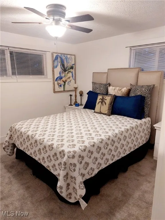 Bedroom featuring a textured ceiling, carpet floors, and a ceiling fan