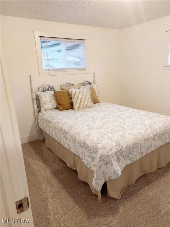 Carpeted bedroom featuring a textured ceiling and baseboards