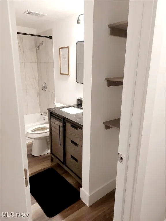 Bathroom featuring vanity, shower / tub combination, and dark wood-type flooring