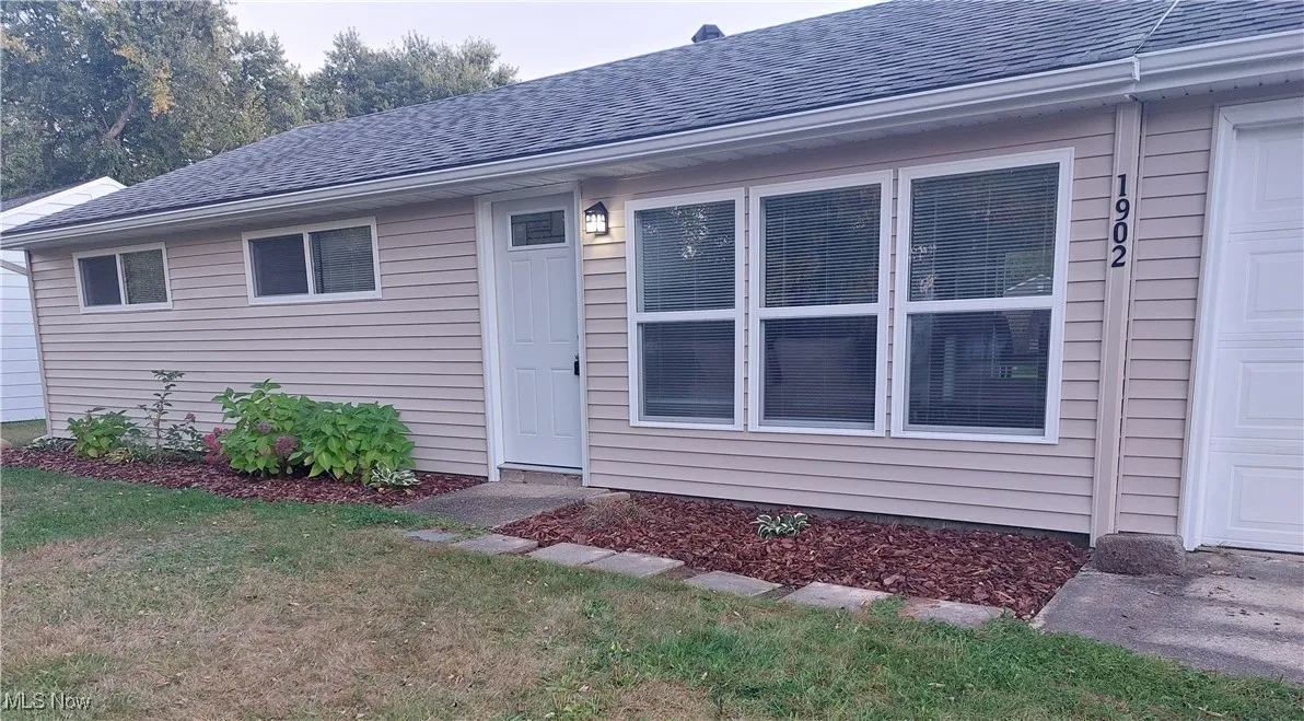 Property entrance with roof with shingles and a yard