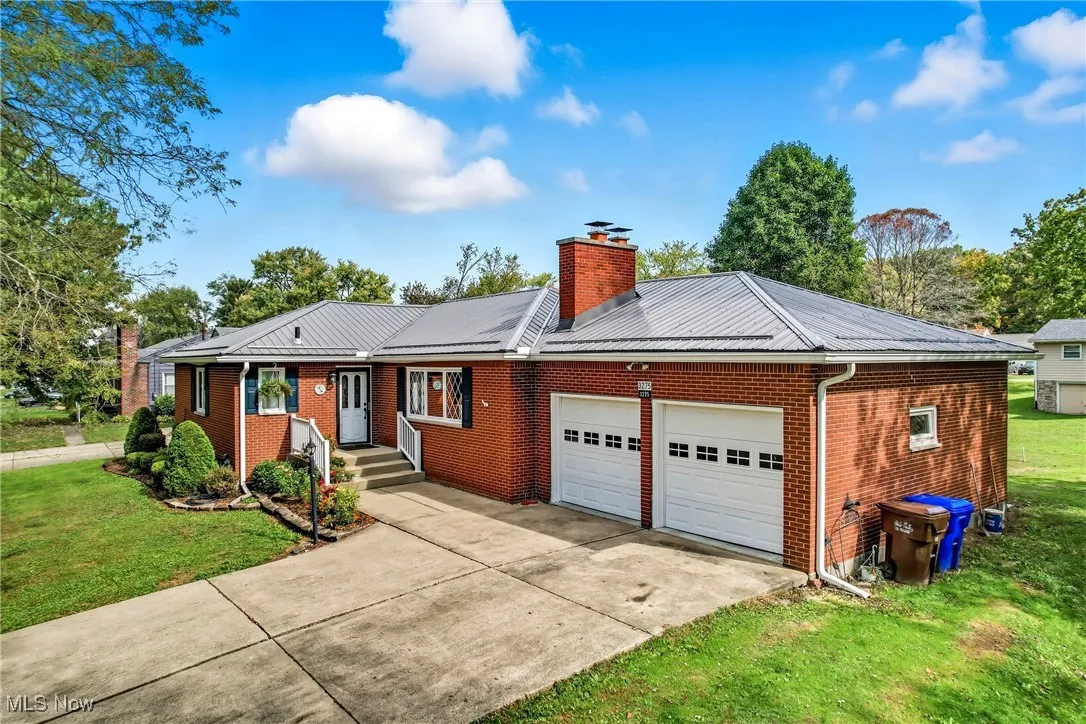 Concrete driveway leads up to the garage, framed by a neatly trimmed lawn.