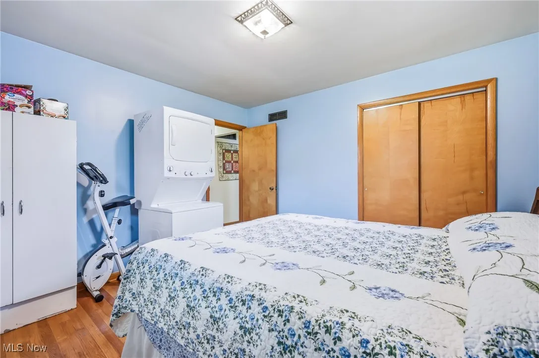 Another angle of the same blue bedroom highlights the ample closet space with wood doors and the practical layout that accommodates both sleeping and laundry areas. The room’s fresh color palette and natural wood trim add to its bright, cheerful character.
