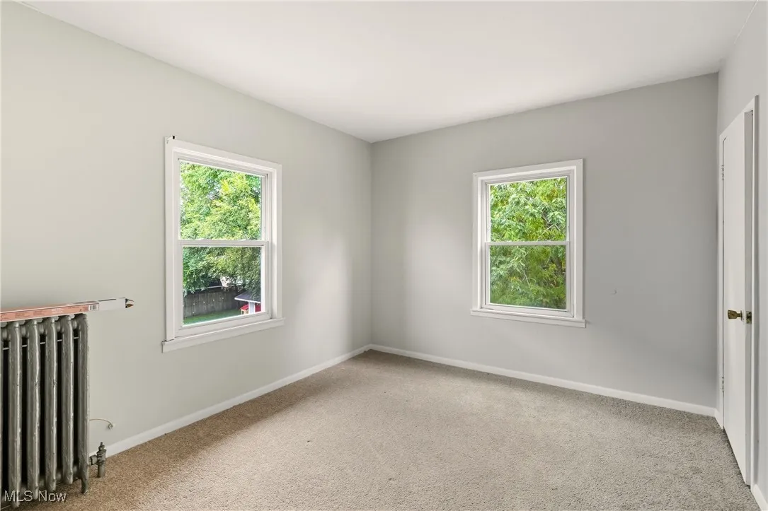 Empty room with radiator and light carpet