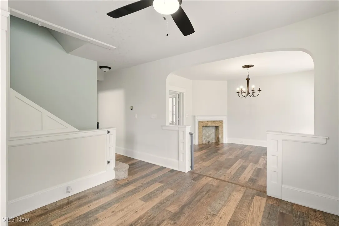 Foyer with arched walkways, a fireplace, dark wood-style floors, and ceiling fan