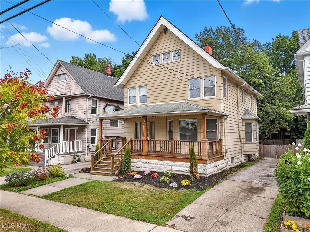 American foursquare style home with covered porch, a front yard, and a chimney