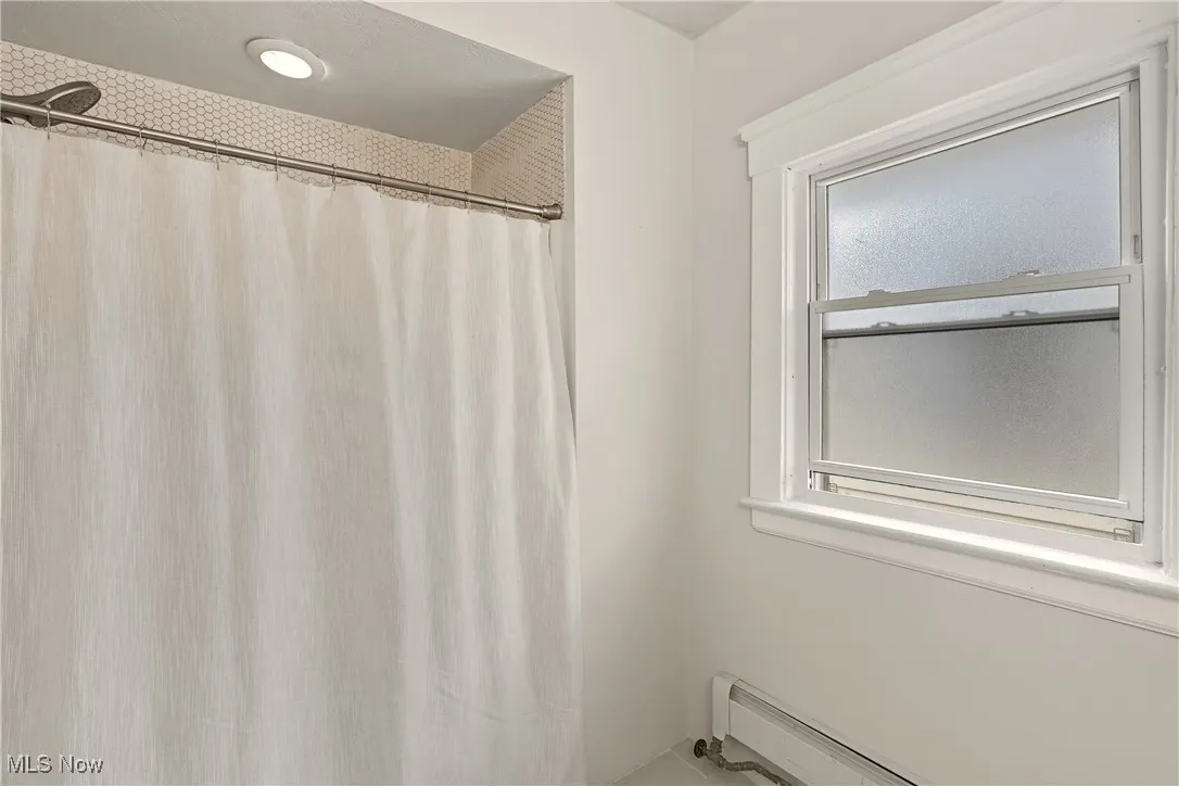 Bathroom with a baseboard radiator and a shower with shower curtain
