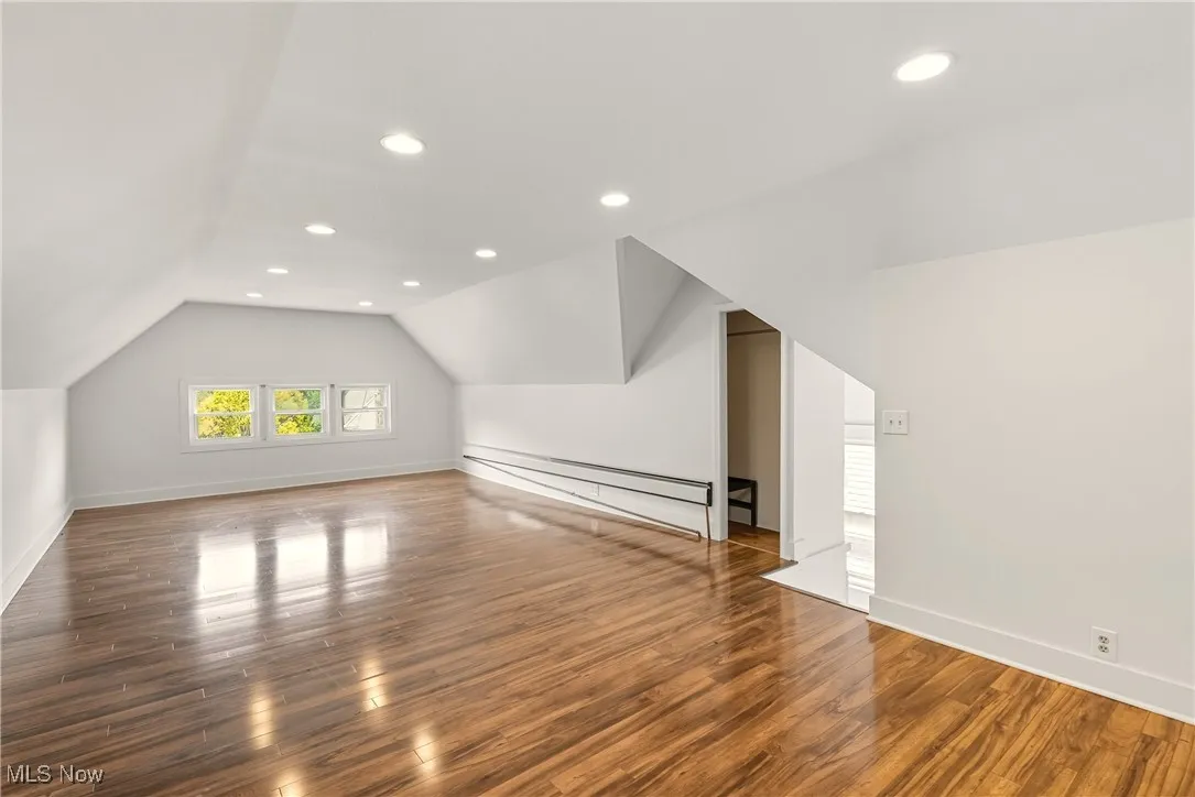Additional living space with dark wood-type flooring, lofted ceiling, recessed lighting, and a baseboard heating unit