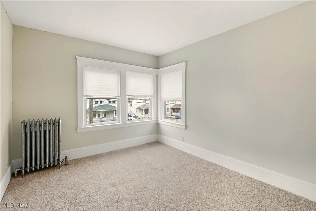 Carpeted bedroom with radiator heating unit and baseboards