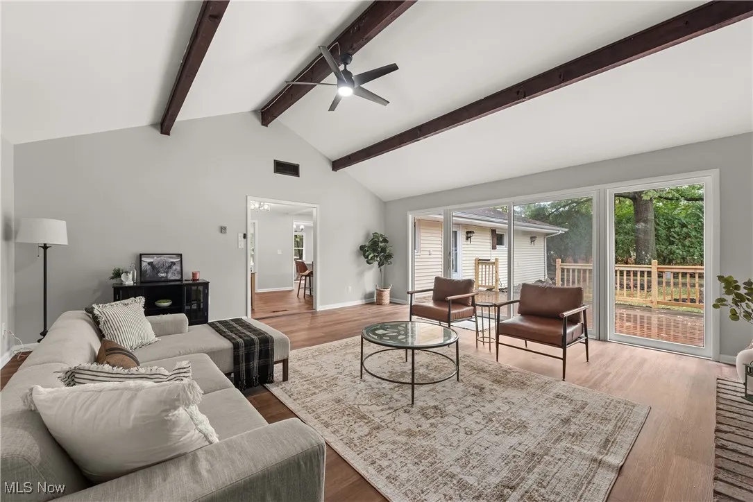 Living room featuring light wood-style floors, high vaulted ceiling, ceiling fan, and beam ceiling