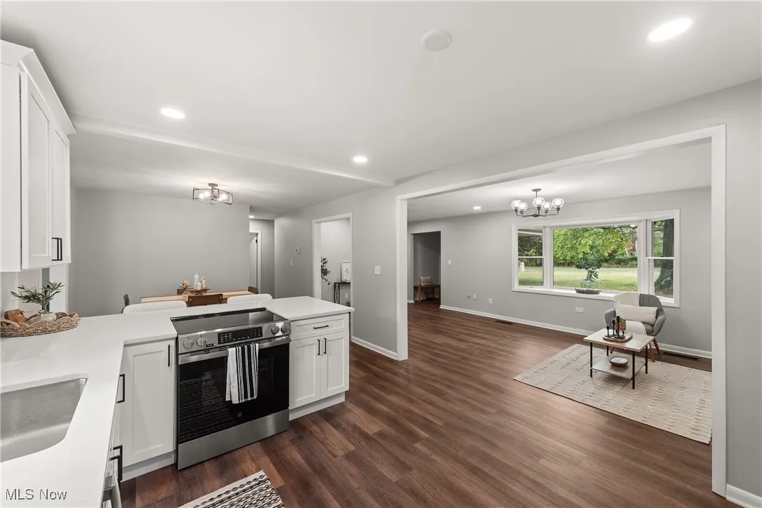 Kitchen with stainless steel electric range oven, white cabinetry, a peninsula, recessed lighting, and dark wood-type flooring