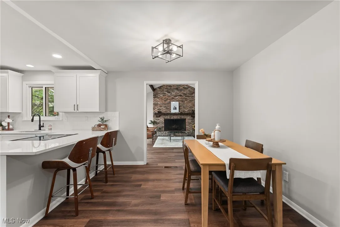 Dining space featuring dark wood-type flooring, recessed lighting, and a fireplace