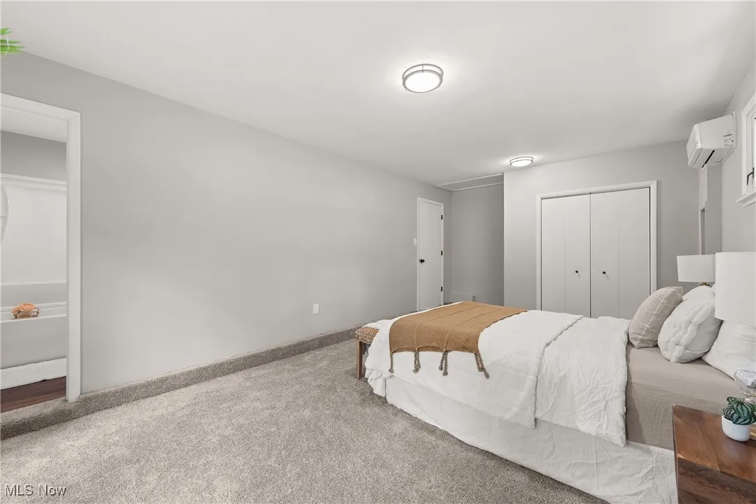 Carpeted bedroom featuring a closet and an AC wall unit