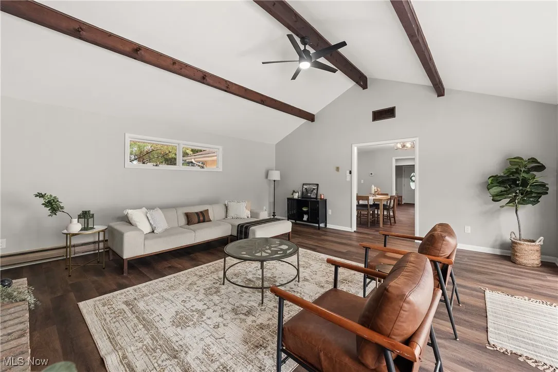 Living room featuring ceiling fan, a baseboard radiator, high vaulted ceiling, dark wood-style floors, and beam ceiling
