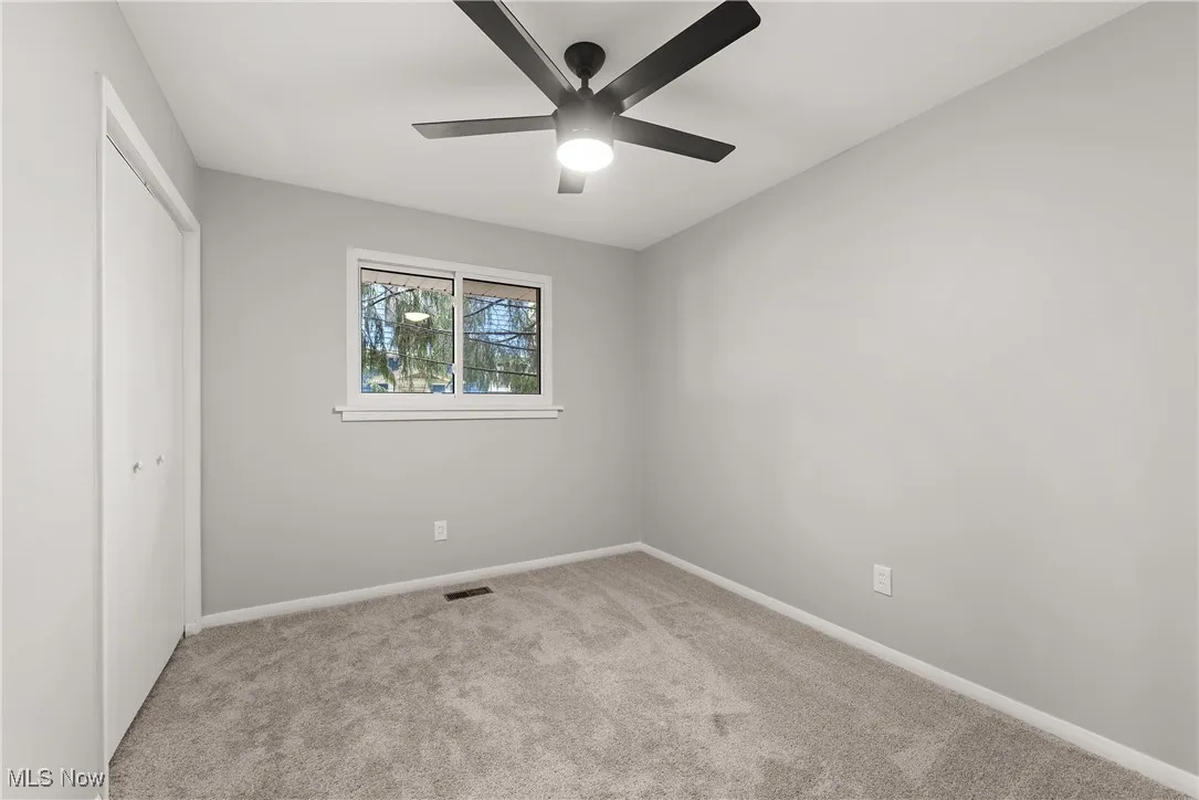 Unfurnished bedroom featuring light carpet, a closet, and a ceiling fan