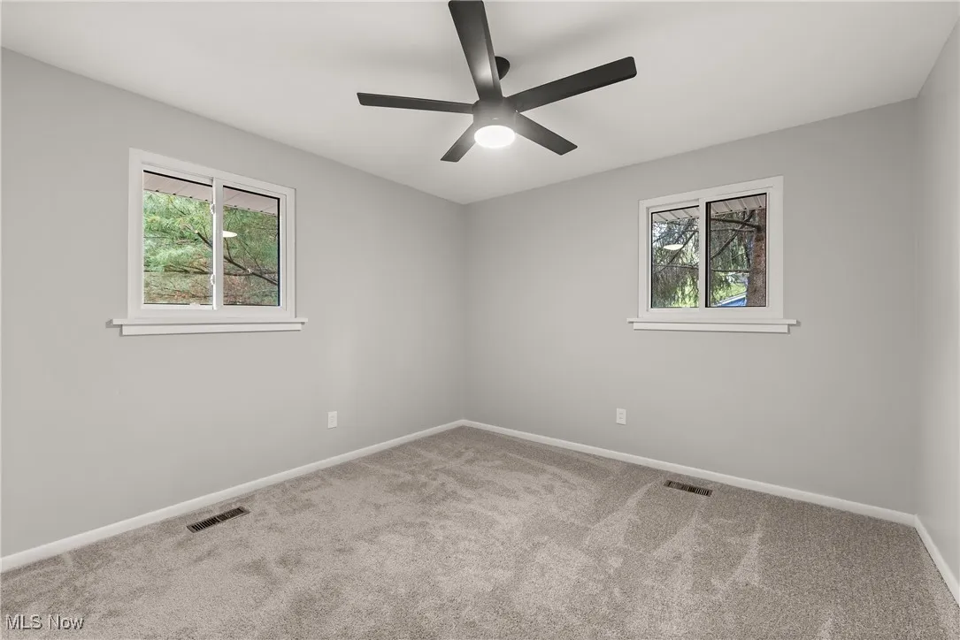Carpeted spare room with baseboards and a ceiling fan