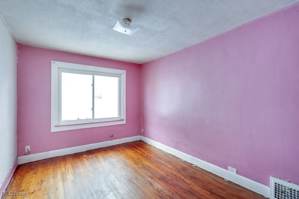 Spare room with wood-type flooring and a textured ceiling