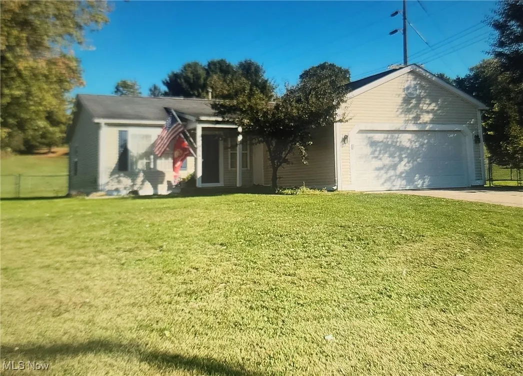 View of front of home with concrete driveway, a front yard, and a garage