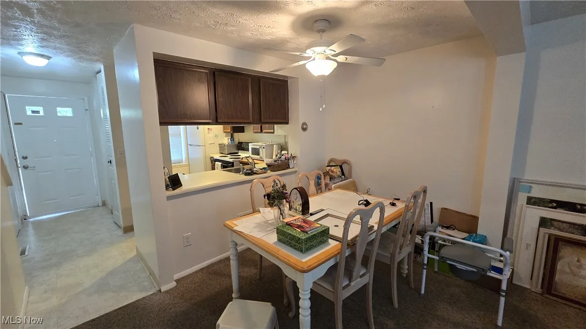 Carpeted dining room featuring a textured ceiling and ceiling fan