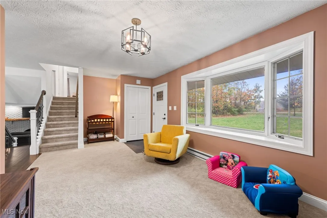 Sitting room featuring stairway, carpet, baseboard heating, a textured ceiling, and a chandelier