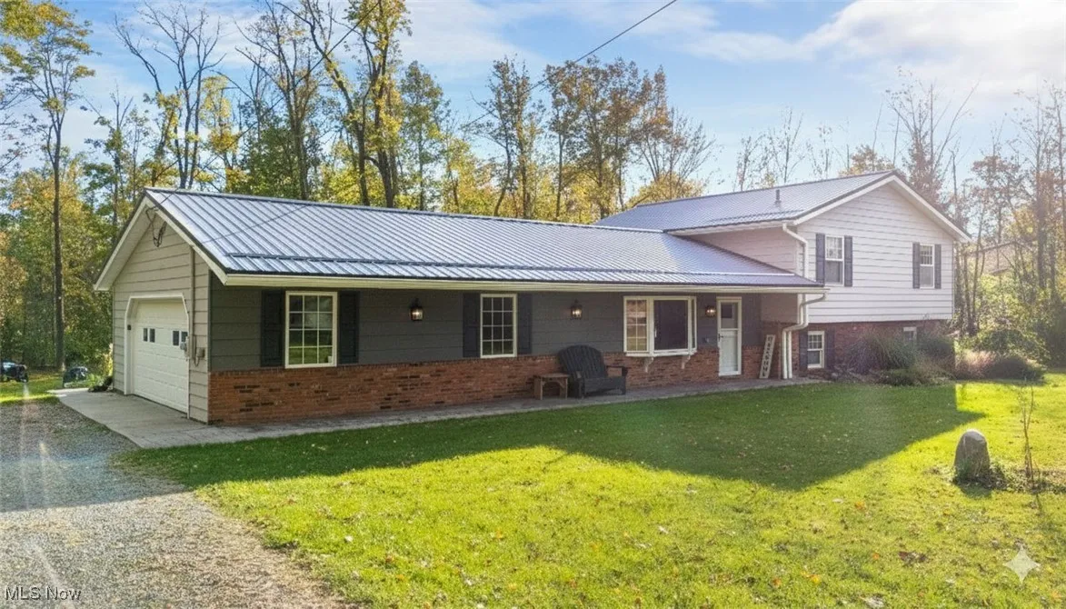 Tri-level home with brick siding, a metal roof, and a front yard