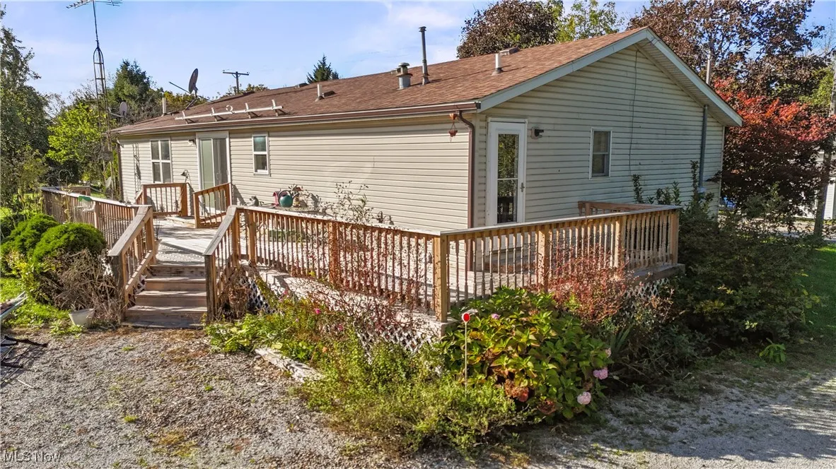 Back of property with a deck and roof with shingles