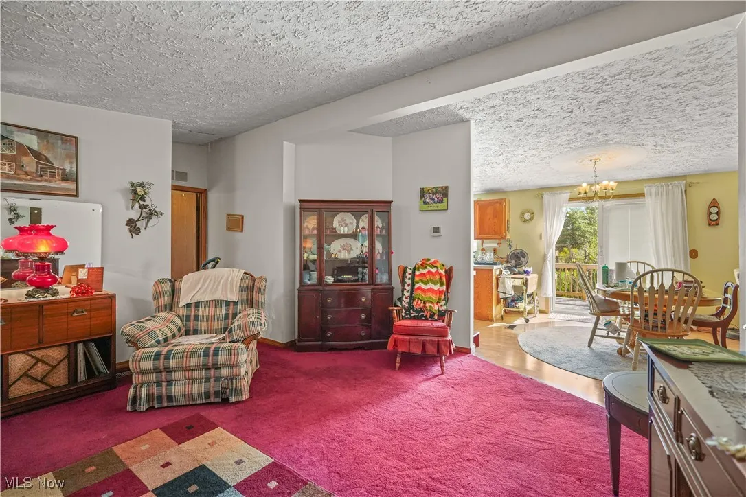 Living room featuring a textured ceiling, a chandelier, and carpet flooring