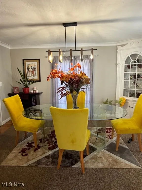 Carpeted dining room with crown molding
