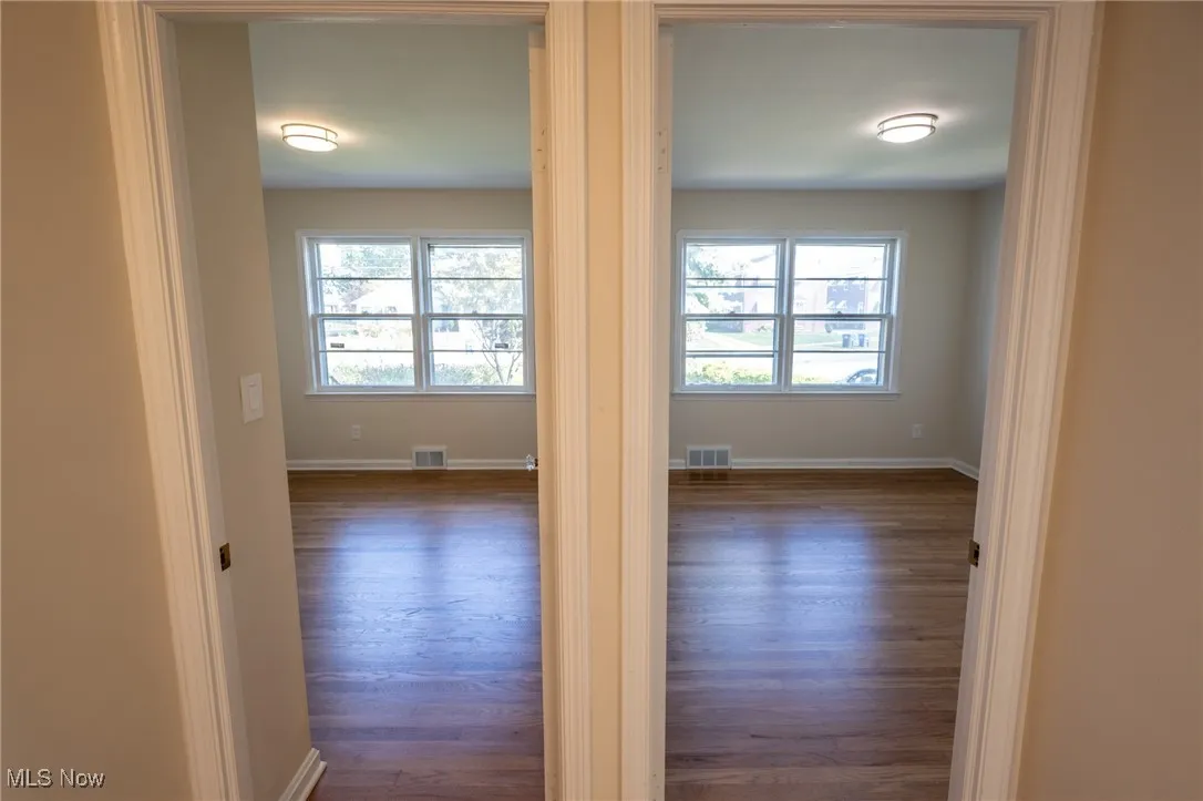 Spare room with dark wood-type flooring and baseboards