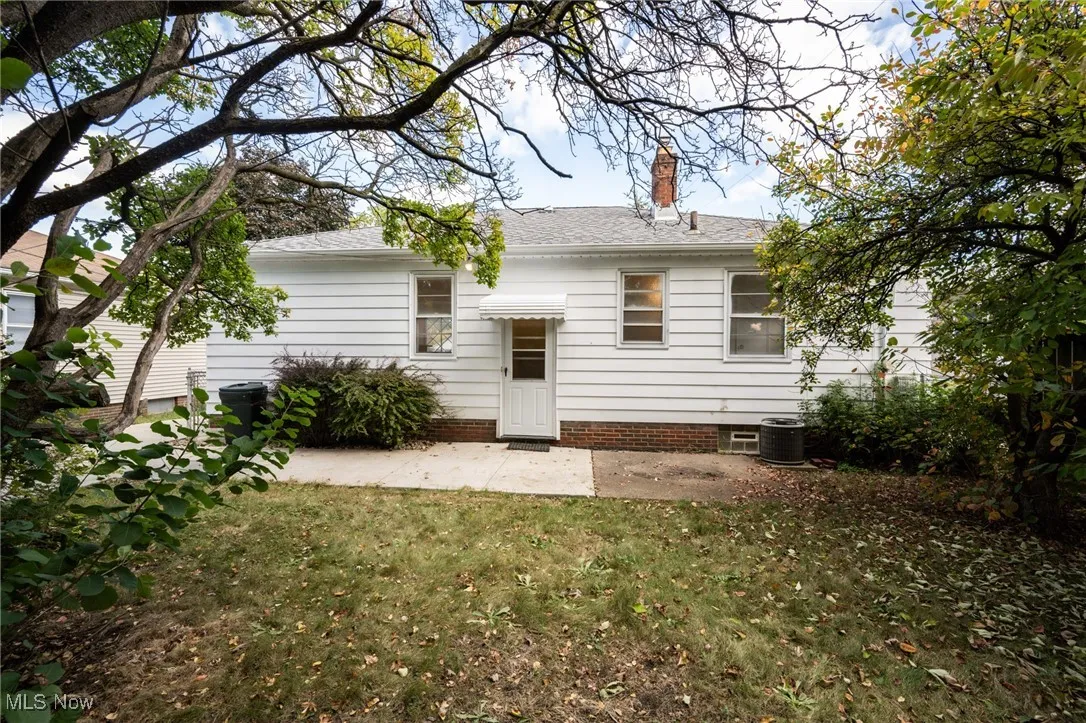 Rear view of property with a patio area, a yard, a chimney, and a shingled roof
