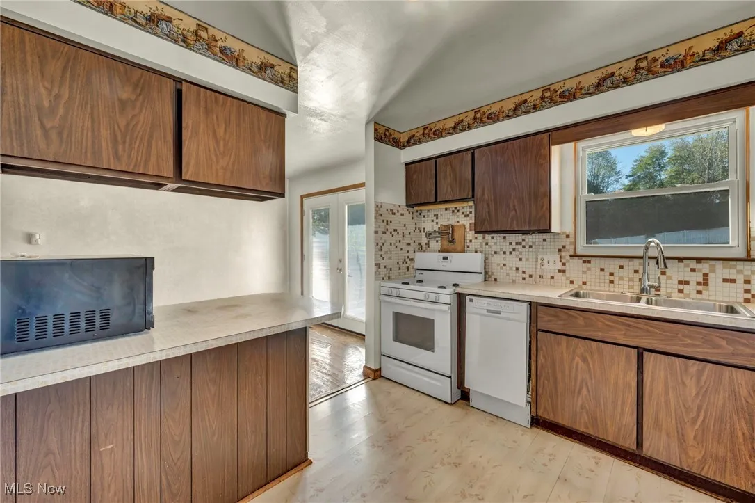 Kitchen featuring white appliances, brown cabinets, light wood-type flooring, and light countertops