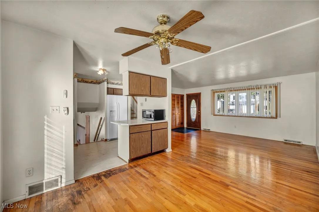 Kitchen featuring open floor plan, light wood-style flooring, brown cabinets, light countertops, and white fridge with ice dispenser