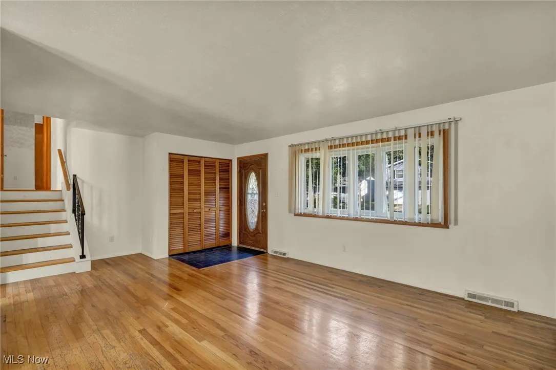Unfurnished living room with stairway and wood-type flooring