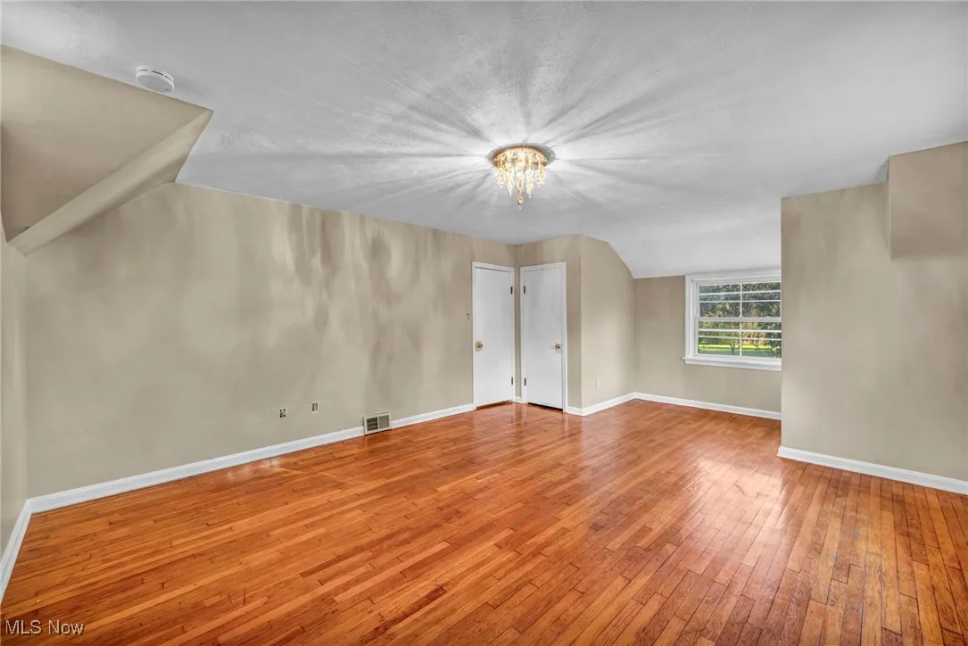 Unfurnished room featuring light wood-style flooring, a chandelier, and vaulted ceiling