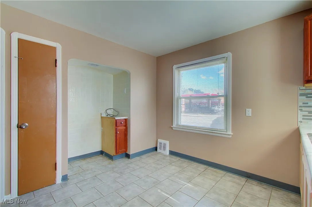 Unfurnished dining area with light tile patterned floors and baseboards