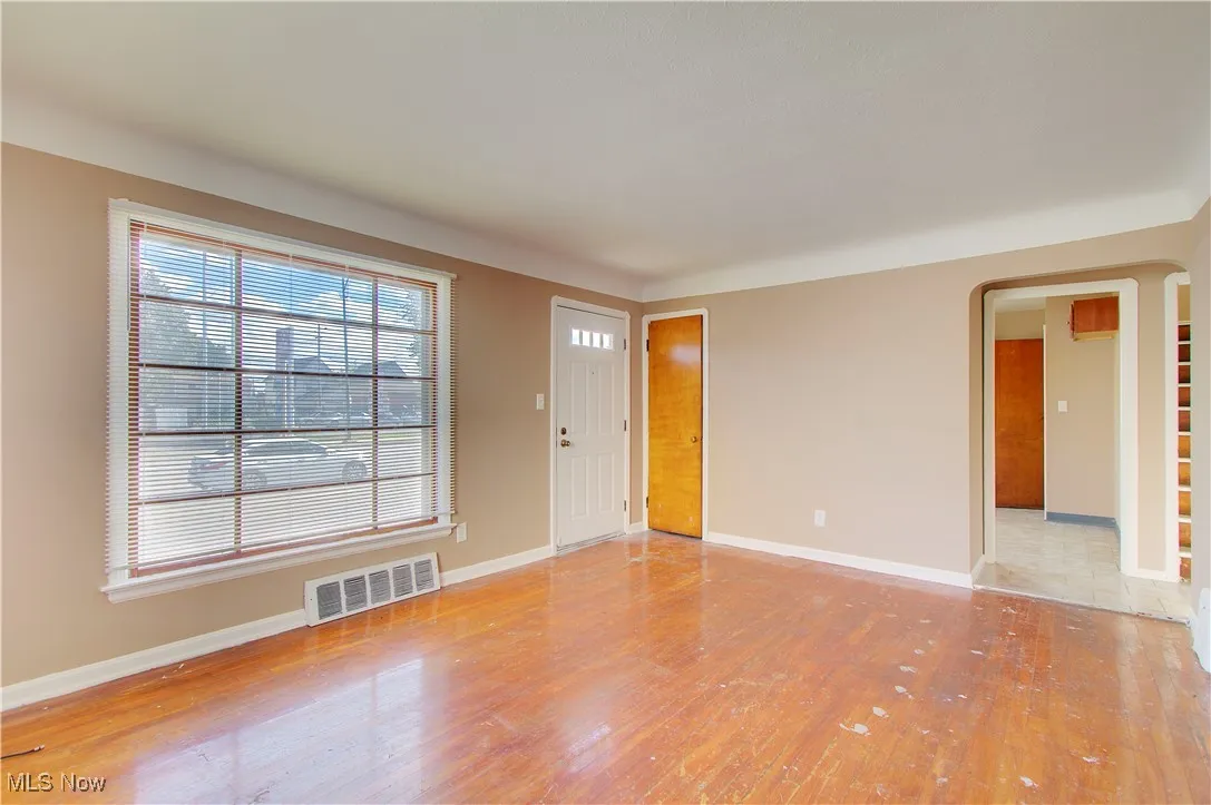 Unfurnished living room with hardwood / wood-style floors and arched walkways