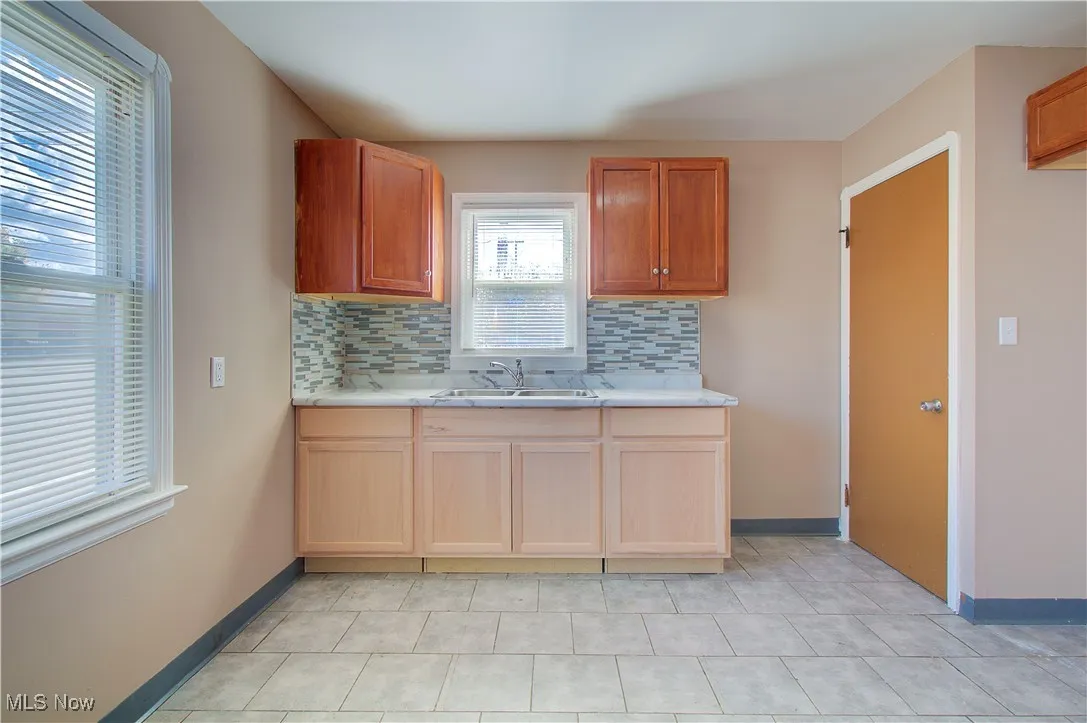 Kitchen with backsplash, light countertops, and light tile patterned floors