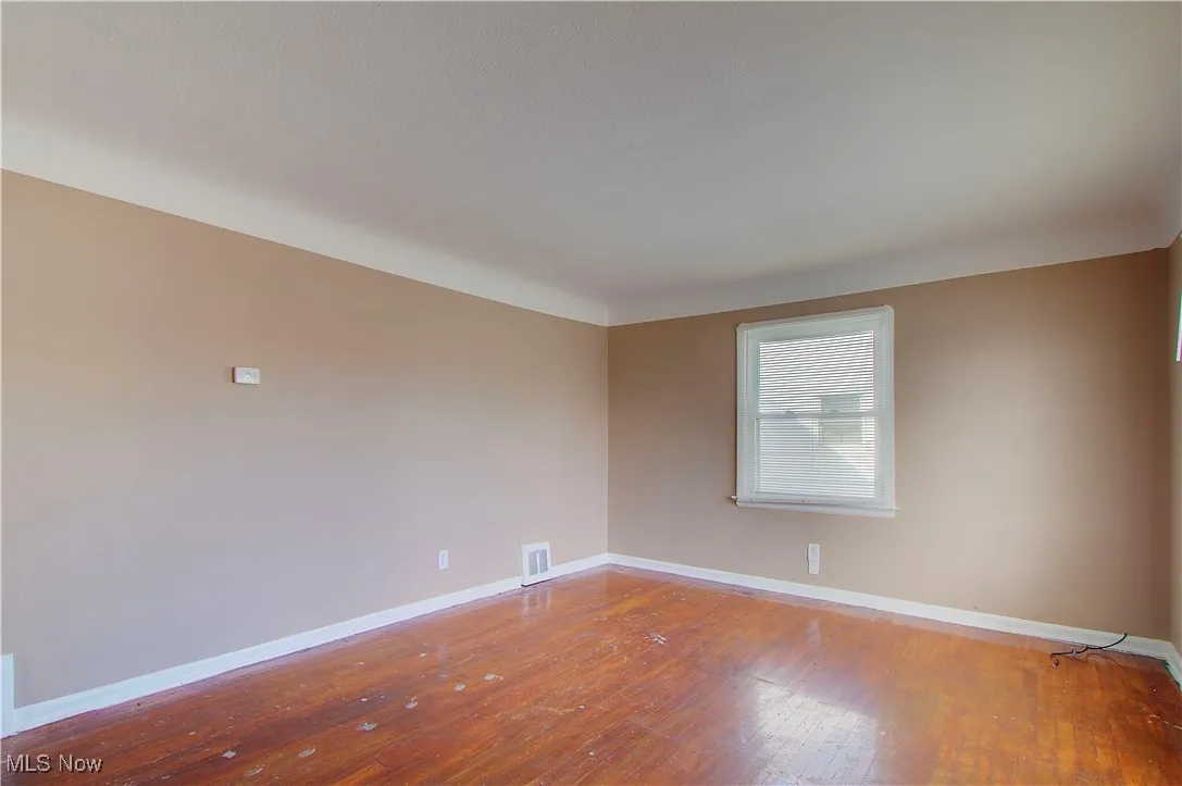 Unfurnished room with baseboards and hardwood / wood-style flooring