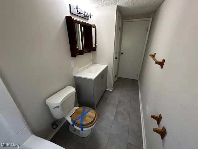 Bathroom featuring vanity, dark tile patterned flooring, and a textured ceiling