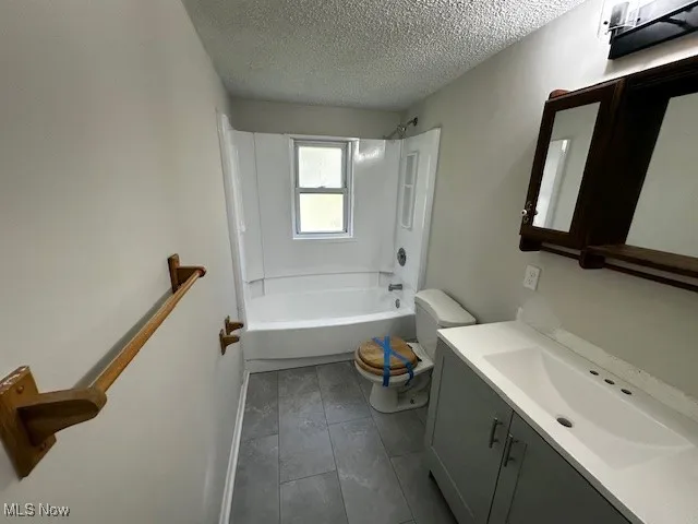 Full bathroom featuring washtub / shower combination, vanity, and a textured ceiling