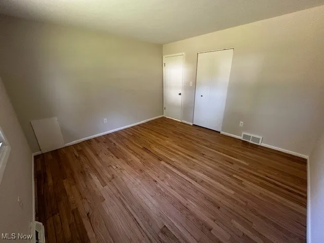 Unfurnished bedroom with wood finished floors and baseboards