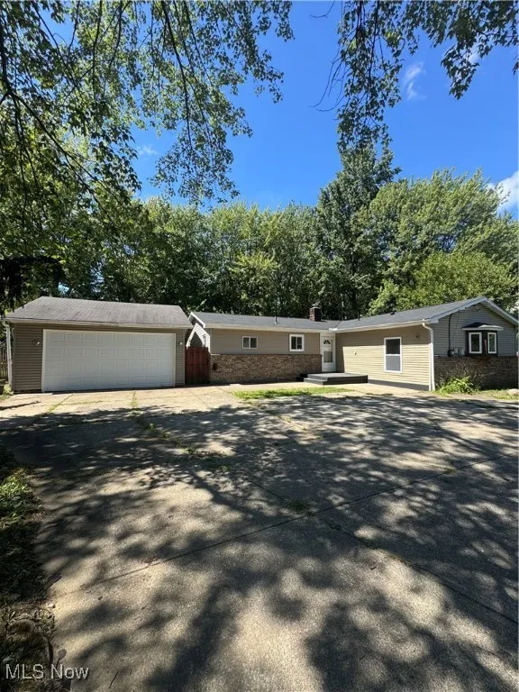 Ranch-style home with a chimney, driveway, and an outbuilding