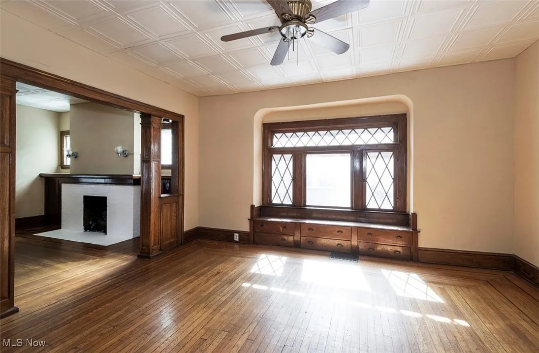 Foyer with hardwood / wood-style floors, a ceiling fan, a brick fireplace, and an ornate ceiling