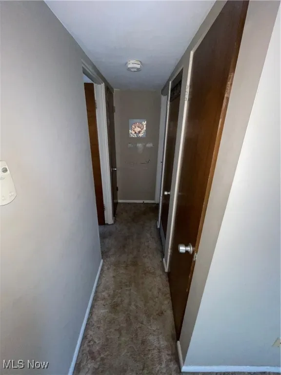 Hallway featuring carpet and baseboards