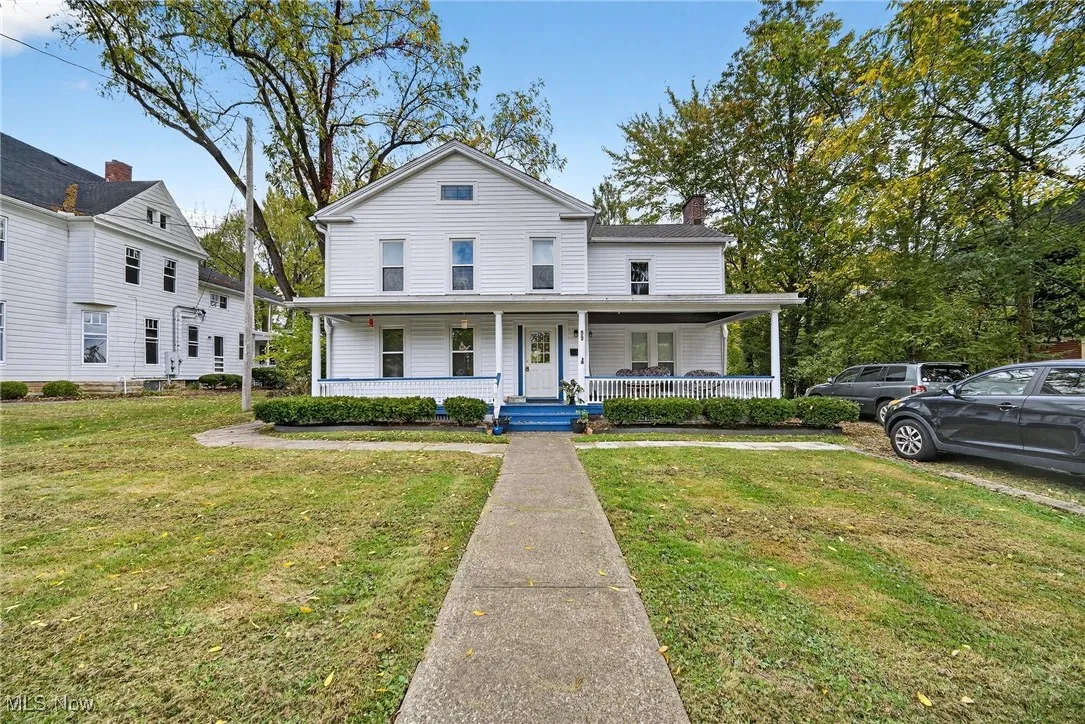View of front facade with a porch, a front lawn, and a chimney