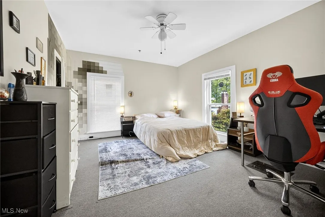 Bedroom with carpet floors, a ceiling fan, and an office area