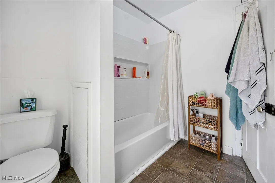Bathroom with shower / tub combo and dark tile patterned flooring