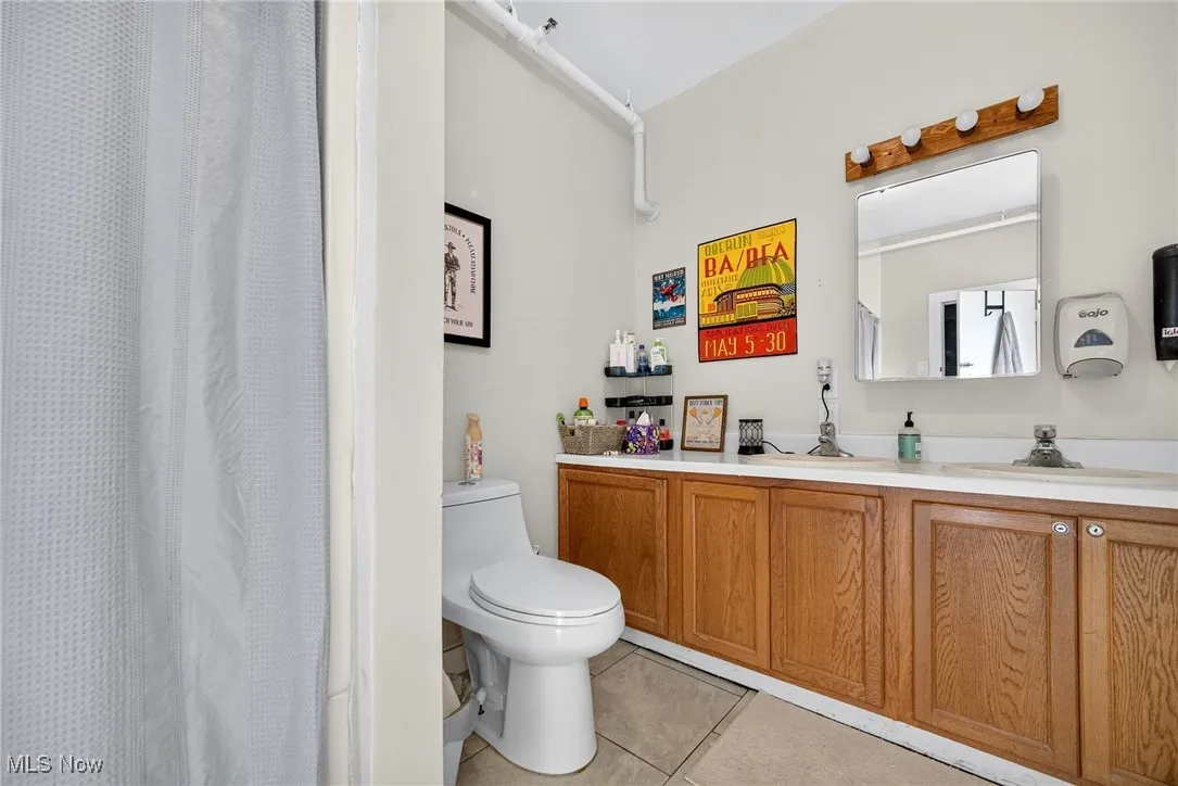 Bathroom with vanity, light tile patterned floors, and a shower with shower curtain
